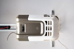 Ceiling mounted projector viewed from below showing vents and mounting bracket in a room