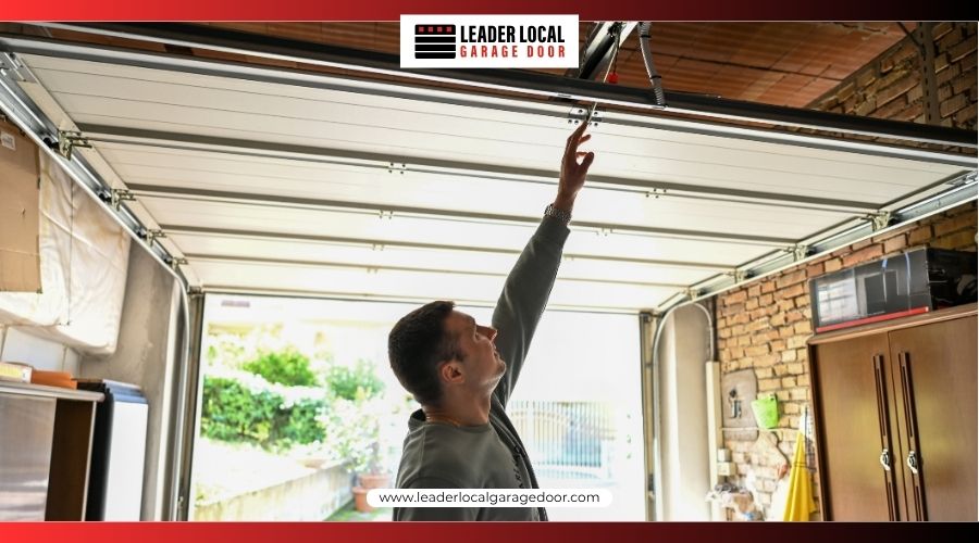 A man reaching up to pull the manual emergency release cord on an open garage door