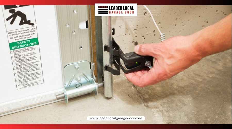 Close-up of a person inspecting a garage door safety photo-eye sensor